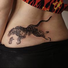 a woman's stomach with a tiger tattoo on her side and the lower part of her belly