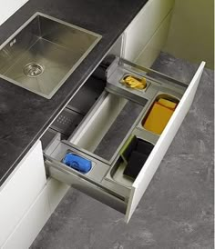 a kitchen sink that is open and has dishes in the bottom drawer next to it