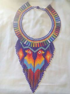 a multicolored beaded necklace is displayed on a white sheet with an orange, yellow, and blue design