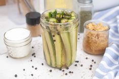 a jar filled with cucumbers sitting on top of a table next to other jars