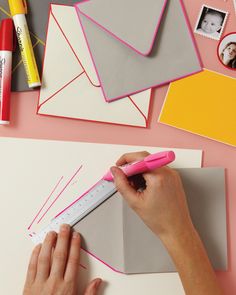 a person using a pink pen to draw on paper with other items surrounding the image