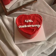 a red heart shaped cake sitting on top of a table