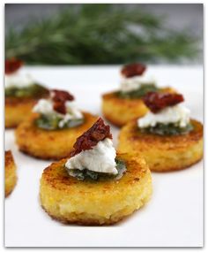 small appetizers are arranged on a white plate with greens and cream toppings