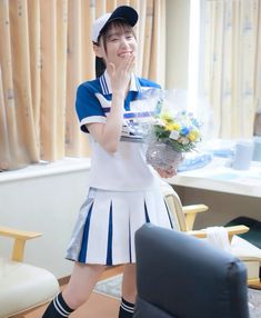 a woman in uniform holding flowers and posing for the camera with her hand on her face