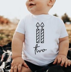 a baby wearing a t - shirt with two candles on it