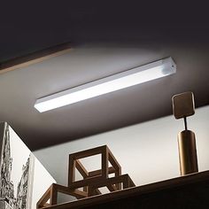 a ceiling light that is on above a shelf in a room with pictures and other items