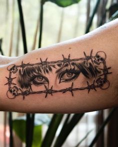 a close up of a person's arm with barbed wire and eyes on it