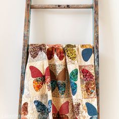 an old ladder is holding a colorful quilt