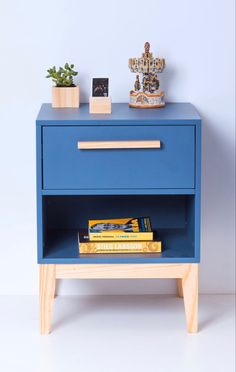 a blue nightstand with two books on it and a potted plant next to it