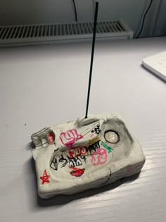 an old cell phone has been decorated with graffiti and is sitting on a table next to a laptop