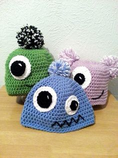 three crocheted hats with googly eyes and ears are sitting on a table