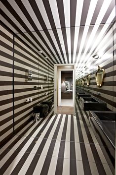 a bathroom with black and white stripes on the walls, sinks and mirrors in it