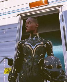 a woman standing in front of a trailer with an alien costume on and holding a motorcycle helmet