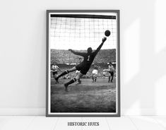 a black and white photo of a goalie catching a soccer ball in the air