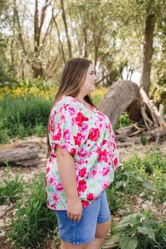 ALL SALES FINAL NOT ELIGIBLE FOR RETURN Experience the beauty of nature with our Juliette Floral Top. The elegant white top is adorned with vibrant pink, red, green, and blue florals, giving it a romantic touch. Its satiny feel and flattering v neck make it the perfect top for any occasion. Fits true to size. Model is wearing a 1X and is 5'7". Size Chart Length Bust 1x 28" 56" 2x 28" 58" 3x 29" 60" *All measurements are approximate and done while hanging.* Fabric and Care 100% Polyester Hand was Floral Print V-neck Blouse For Garden Party, Tiered Dresses, Teen Dress, Hanging Fabric, Blue Florals, Spring Fits, White Outfits, Green And Blue, Floral Top