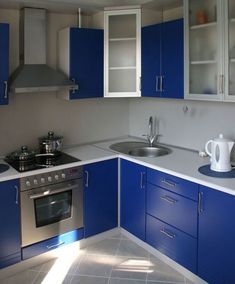 a kitchen with blue cabinets and stainless steel appliances, including a coffee pot on the stove