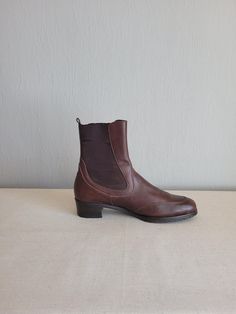 These Vintage Leather Chelsea Booties in Brown by Salvatore Ferragamo offer timeless elegance with a casual twist. Made in Italy, these flat pull-on boots feature a classic round toe and low heel for all-day comfort. The rich brown leather showcases the brand's signature craftsmanship, while the iconic Chelsea boot design, complete with elastic side panels, ensures a snug fit and effortless wear. Perfect for both casual and refined outfits, these versatile boots add understated luxury to any war Low Heel Flats, Pull On Boots, Designer Boots, Vintage Leather, Low Heels, Boot Shoes Women, Salvatore Ferragamo, Snug Fit, Stylish Women