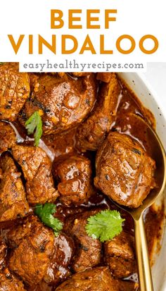 beef vindaloo in a white bowl with a gold spoon and cilantro garnish