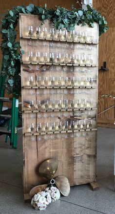 a wooden display with candles and flowers on the floor next to an arrangement of wine glasses