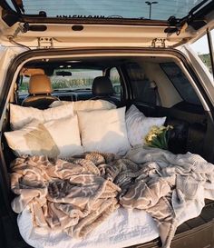 the back end of a car with blankets and pillows in it's trunk area