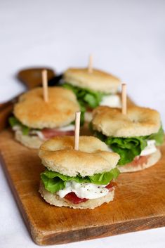 mini sandwiches with toothpicks in them on a wooden cutting board, ready to be eaten