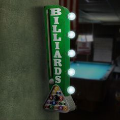 a billiards sign hanging on the side of a building with pool balls in it