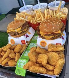 two trays of cheeseburgers and french fries on a table