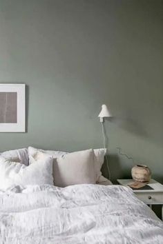 a white bed sitting in a bedroom next to a lamp and pictures on the wall