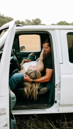 a man and woman sitting in the back of a white truck with their arms around each other