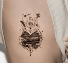 a woman's stomach with a book and compass tattoo on her left side ribcage