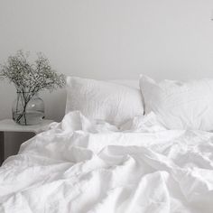 an unmade bed with white linens and pillows in a minimalistic bedroom setting