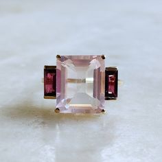 ITEM DESCRIPTION: >> The Ring is made from Solid 14K Yellow Gold. Gemstone used is absolutely natural and ethically sourced. >> Natural Rose Quartz & Rhodolite Garnet in prong setting is studded on it with utmost precision. >> This is a minimalist design which makes it a hassle free and everyday jewelry. >>Center Gem: Rose Quartz Center Gem size: 12x10 mm Center Gem weight: 5.70 ct >>Side gemstone: Rhodolite Garnet Side Gems size: 6x3 mm Gem weight: 1.15 carats Gold purity: 14K (58.33% approx.) Elegant Pink Multi-stone Sapphire Ring, Timeless Pink Jewelry With Center Stone, Elegant Morganite Ring With Gemstone Accents, Formal Morganite Rings With Gemstone Accents, Formal Morganite Ring With Gemstone Accents, Timeless Pink Rings With Center Stone, Elegant Three Stone Ruby Ring, Elegant Pink Multi-stone Rings, Elegant Pink Three Stone Rings