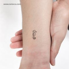 a small seahorse tattoo on the left inner arm and wrist is shown in black ink