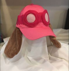 a stuffed animal wearing a pink hat with goggles on it's face and ears