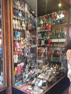 a woman standing in front of a store filled with shoes