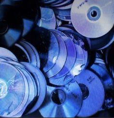 many discs are stacked on top of each other in the dark blue hued background