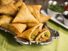 some food is on a silver plate and sits on a green tablecloth next to other dishes