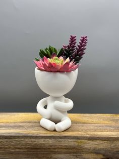 a small white vase filled with flowers on top of a wooden table