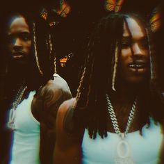 two young men with dreadlocks standing next to each other in front of butterflies