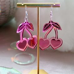 USA-made cherry heart earrings! Made of lightweight durable acrylic plastic and hypoallergenic sterling silver ear hooks. Condition: New. Personally designed, laser-cut, hand-assembled. Measurements: 2" x 1.5" Shipping: Item ships in 4-7 days ♡♡♡♡♡ Earring Care: Acrylic is extremely lightweight and durable, but can get scratched. To avoid this, please handle your earrings with care! Avoid contact with hairspray, perfume, sweat, and water, wipe clean and store away from direct sunlight. To clean Valentine Day Earrings, Magical Stuff, Laser Engraved Earrings, Strawberry Shortcake Characters, Fashionable Earrings, Engraved Earrings, Pink Sparkly, Style Edit, Pink Accessories