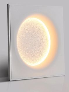 a white square light box with an illuminated object in the middle on a grey surface