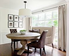 a dining room table with chairs and pictures on the wall above it in front of a window