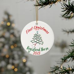 a white ornament hanging from a christmas tree with the words first christmas keychain nurse 2013