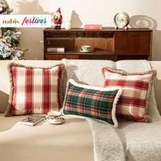 a couch with two pillows and a christmas tree in the corner next to it on top of a coffee table