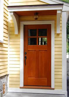 a wooden door on the side of a yellow house