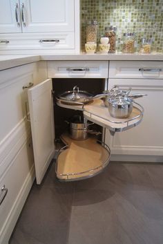 an open cabinet in a kitchen with pots and pans