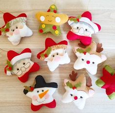 a group of christmas ornaments hanging from strings on a wooden table with white and red decorations