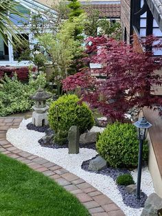 a small garden with rocks and trees in the center, along side a brick walkway