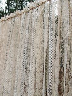 an old lace curtain is hanging from the ceiling in front of some trees and bushes