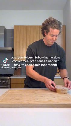 a man standing in front of a wooden cutting board